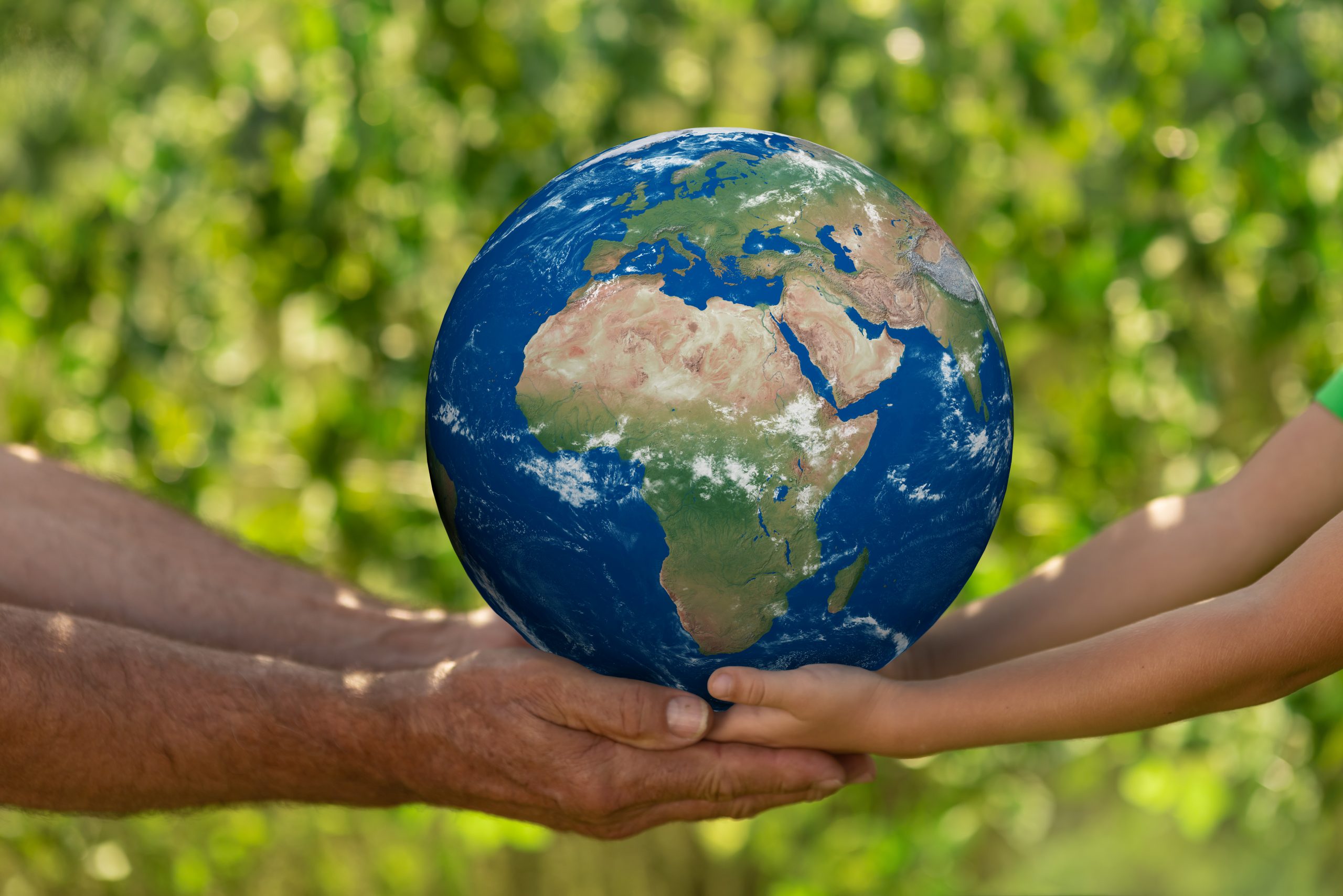 Senior man and child holding blue planet in hands against spring green background. Earth day and ecology concept. Elements of this image furnished by NASA